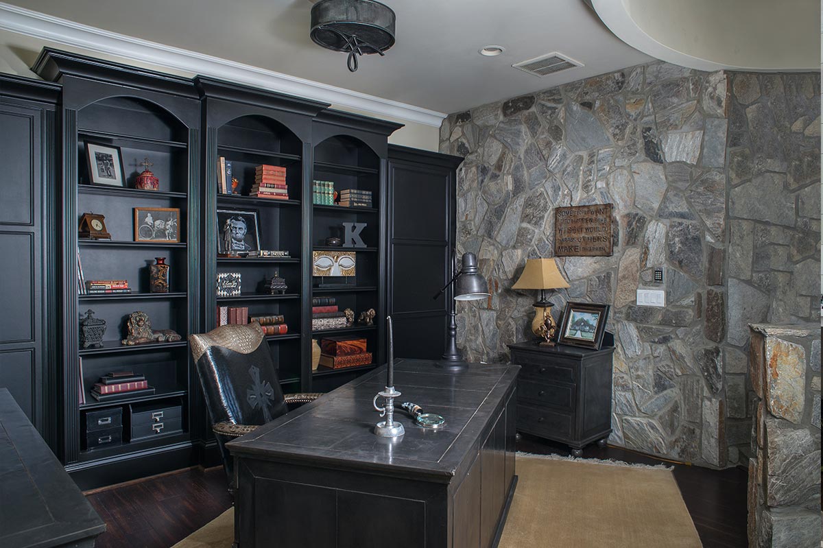 Custom library cabinetry and shelving beside a stone wall