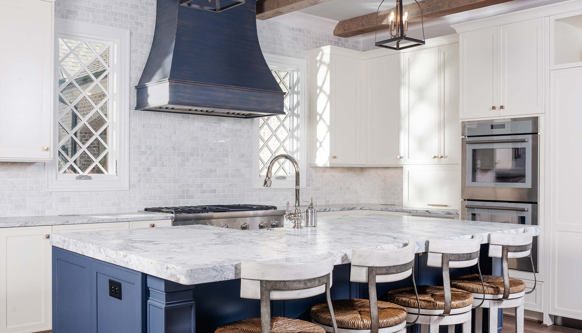 Custom kitchen with a painted range hood, marble island and glass front cabinets